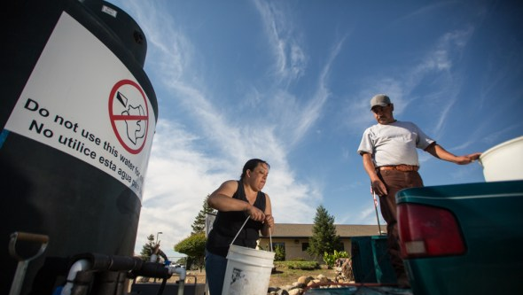 A resident in California's San Joaquin Valley fills jugs from a community water tank during the drinking-water crisis.